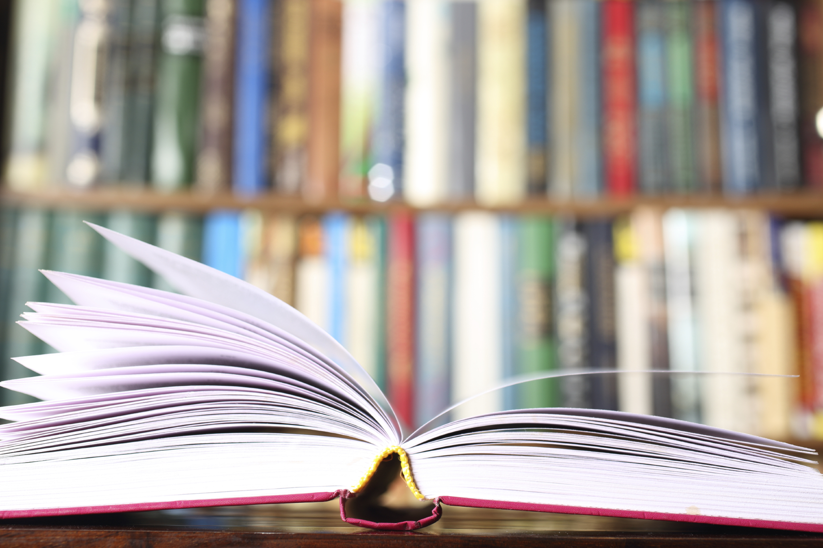 An open book in front of a library shelf