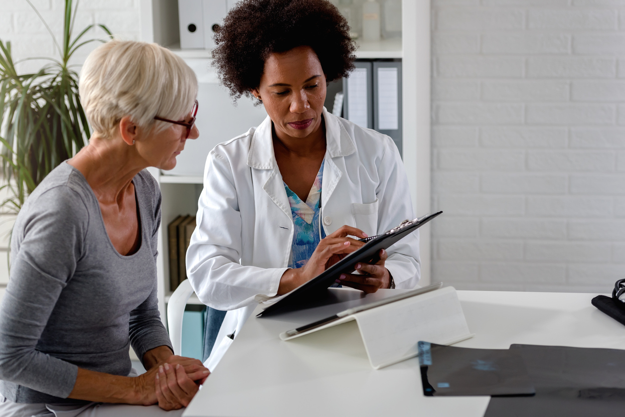 A doctor showing an older woman something on a digital tablet