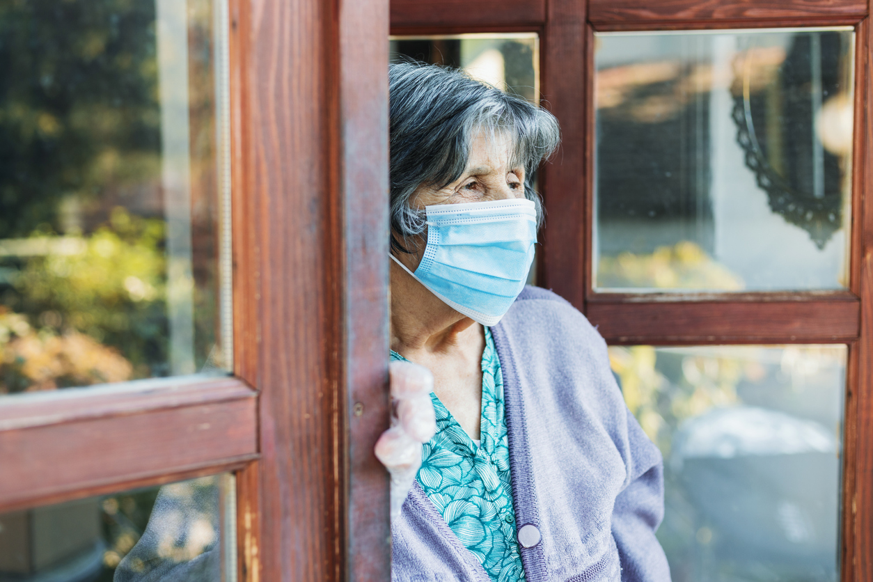 A woman wearing a facemask at an open door
