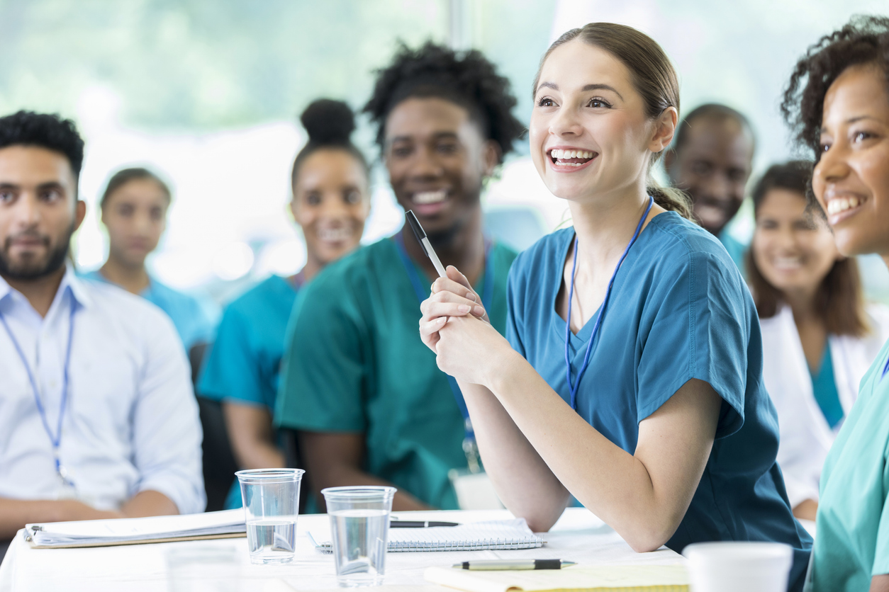 Group of healthcare professionals sat at tables looking in one direction