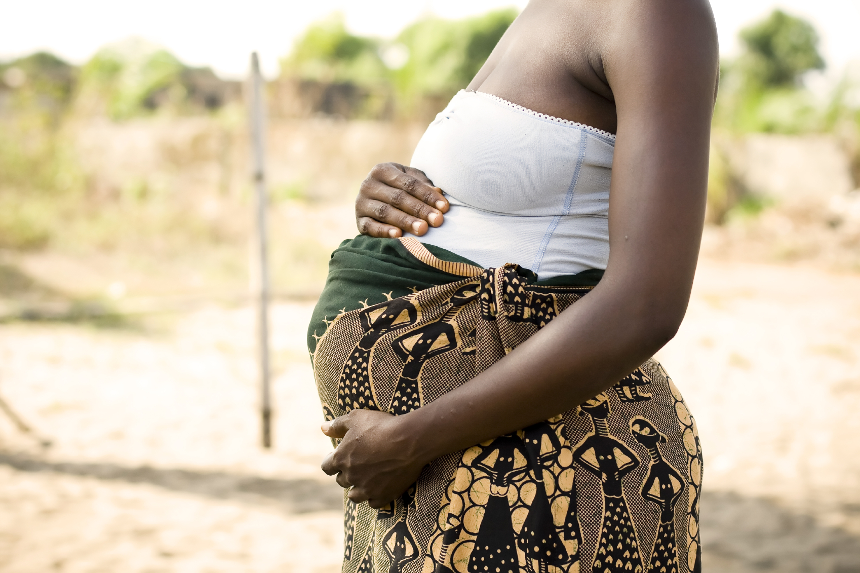 Pregnant woman holding her belly and wearing traditional dress