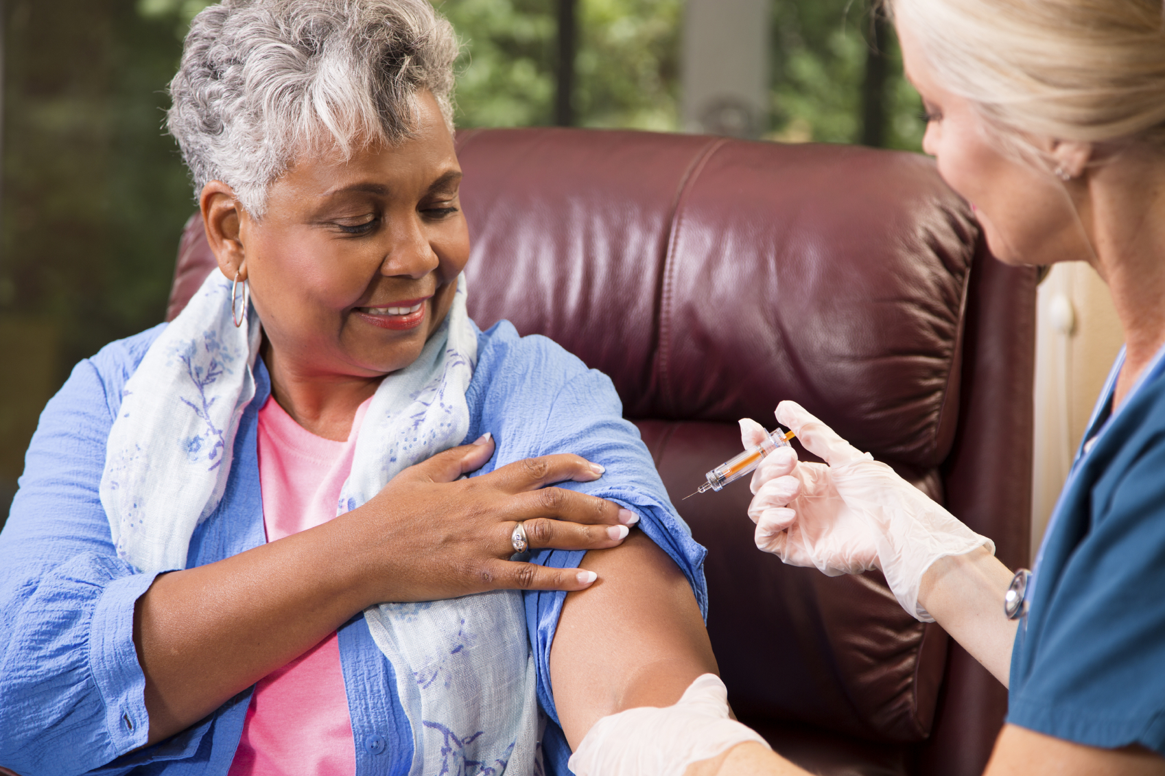 A healthcare professional administering a vaccine to an older woman