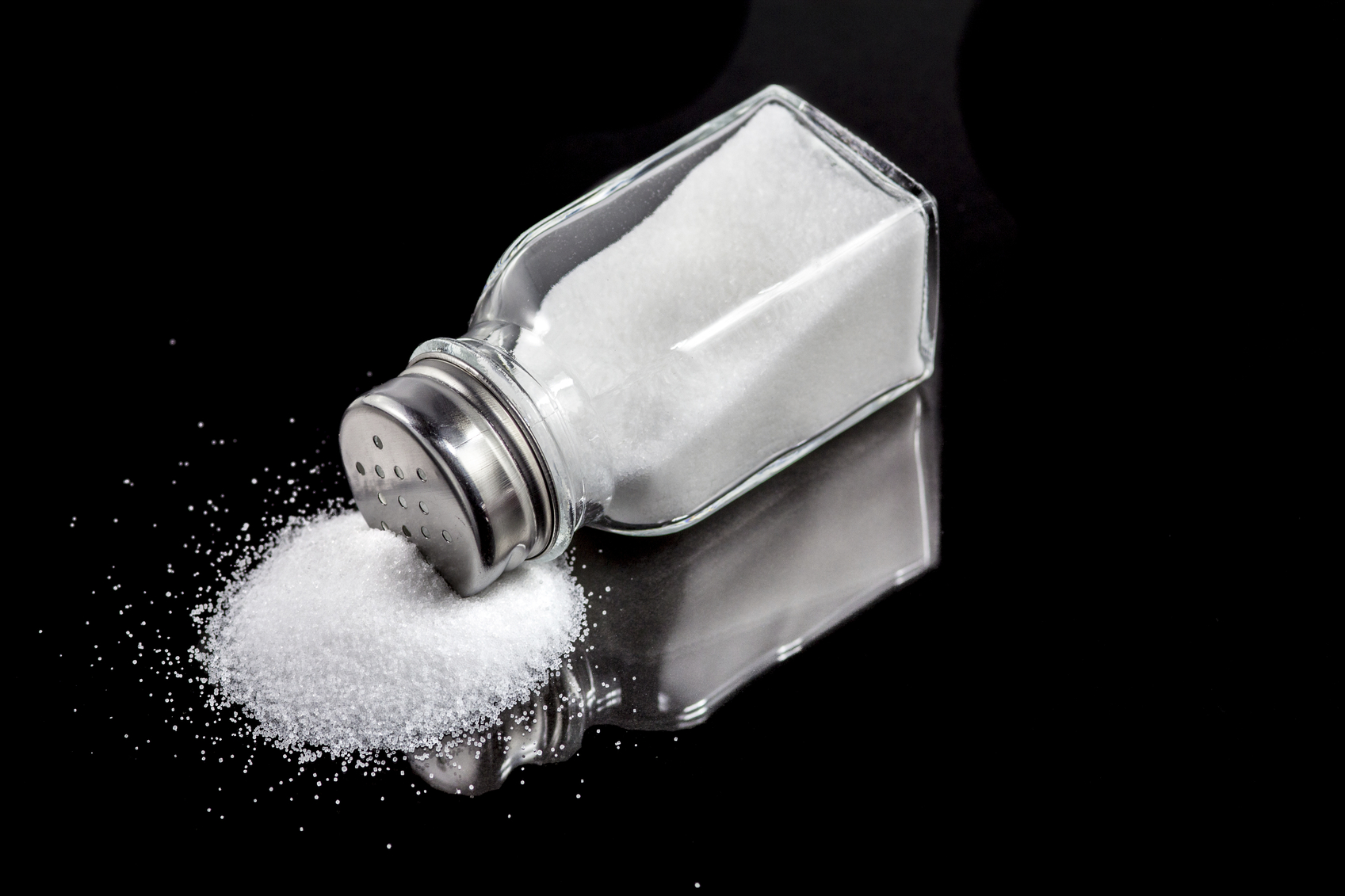 A slat shaker tipped over with salt spilling out