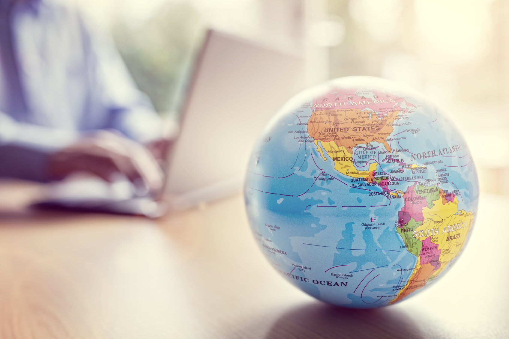 A globe in front of a person on a laptop